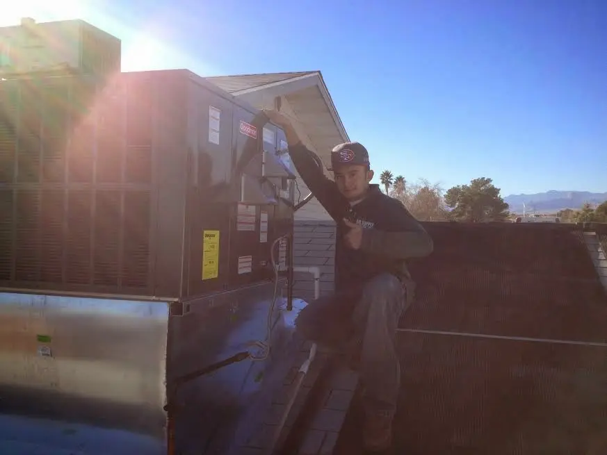 HVAC technician performing AC Tune-Up on a rooftop unit in Huntley